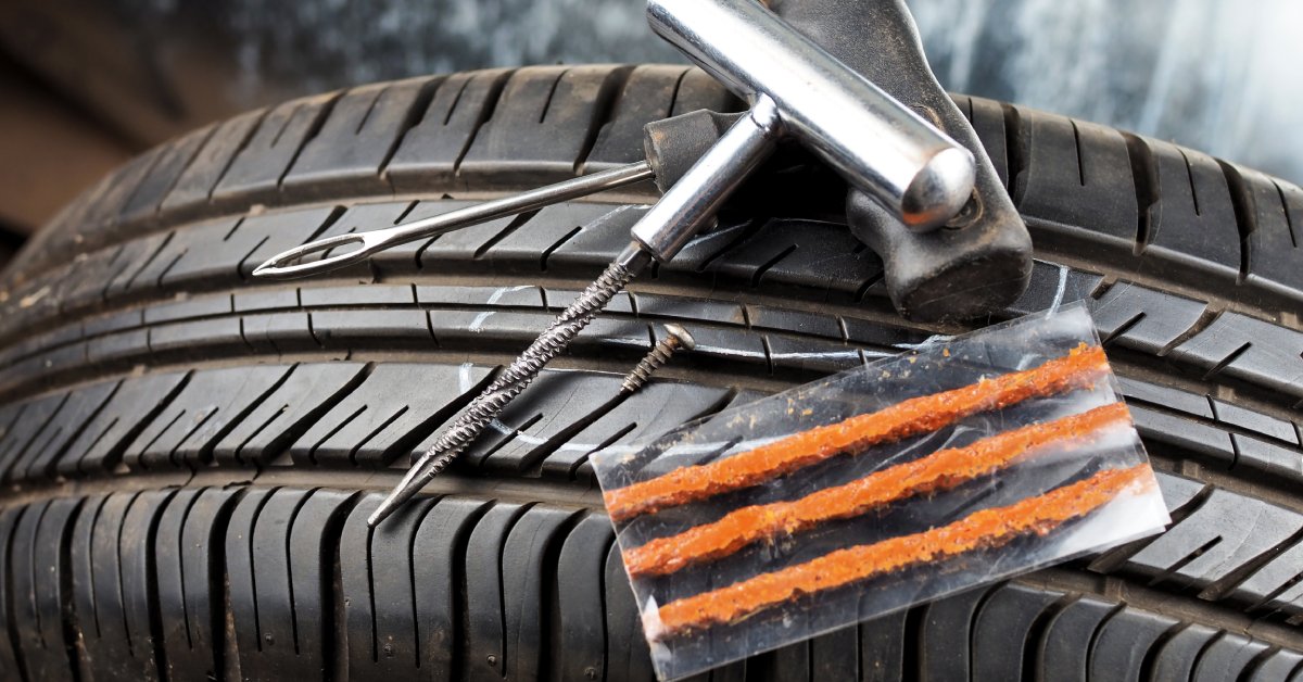 A tire with a tire repair kit sitting on top of it. The kit includes tire plugs and the tools to install the plugs.